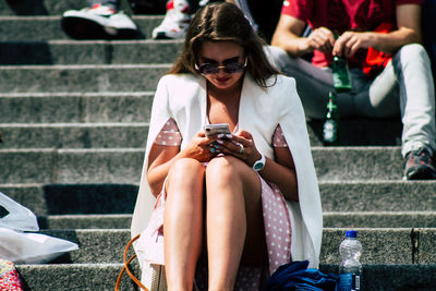 Midsection of woman using smart phone while sitting outdoors