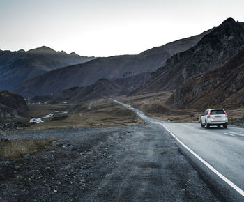 Cars on road by mountain against sky