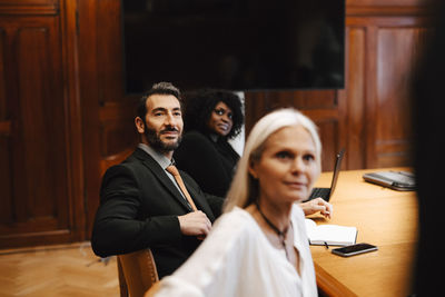 Multiracial colleagues sitting at conference table in board room during meeting