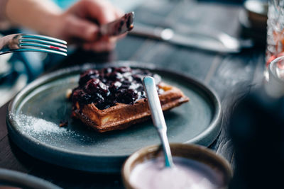 Cropped hands of person eating sweet food on table