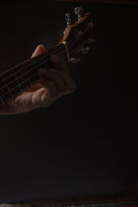Man playing guitar against black background