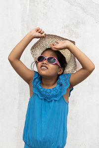 An indian girl wearing sunglasses and holding hat looking at the sun in summer on white background