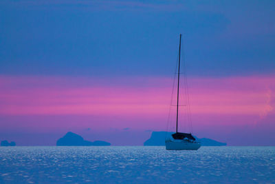 Sailboat in sea against sunset sky