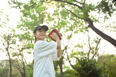 Portrait of young woman standing against tree