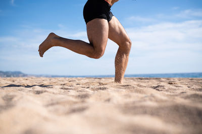 Shot of the legs of an unrecognizable man exercising on the beach. sports concept.	