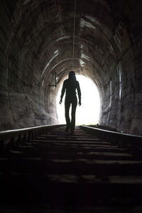 Rear view of silhouette woman standing in tunnel