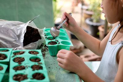 Midsection of girl putting dirt into silicone tray