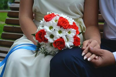 Midsection of couple holding bouquet