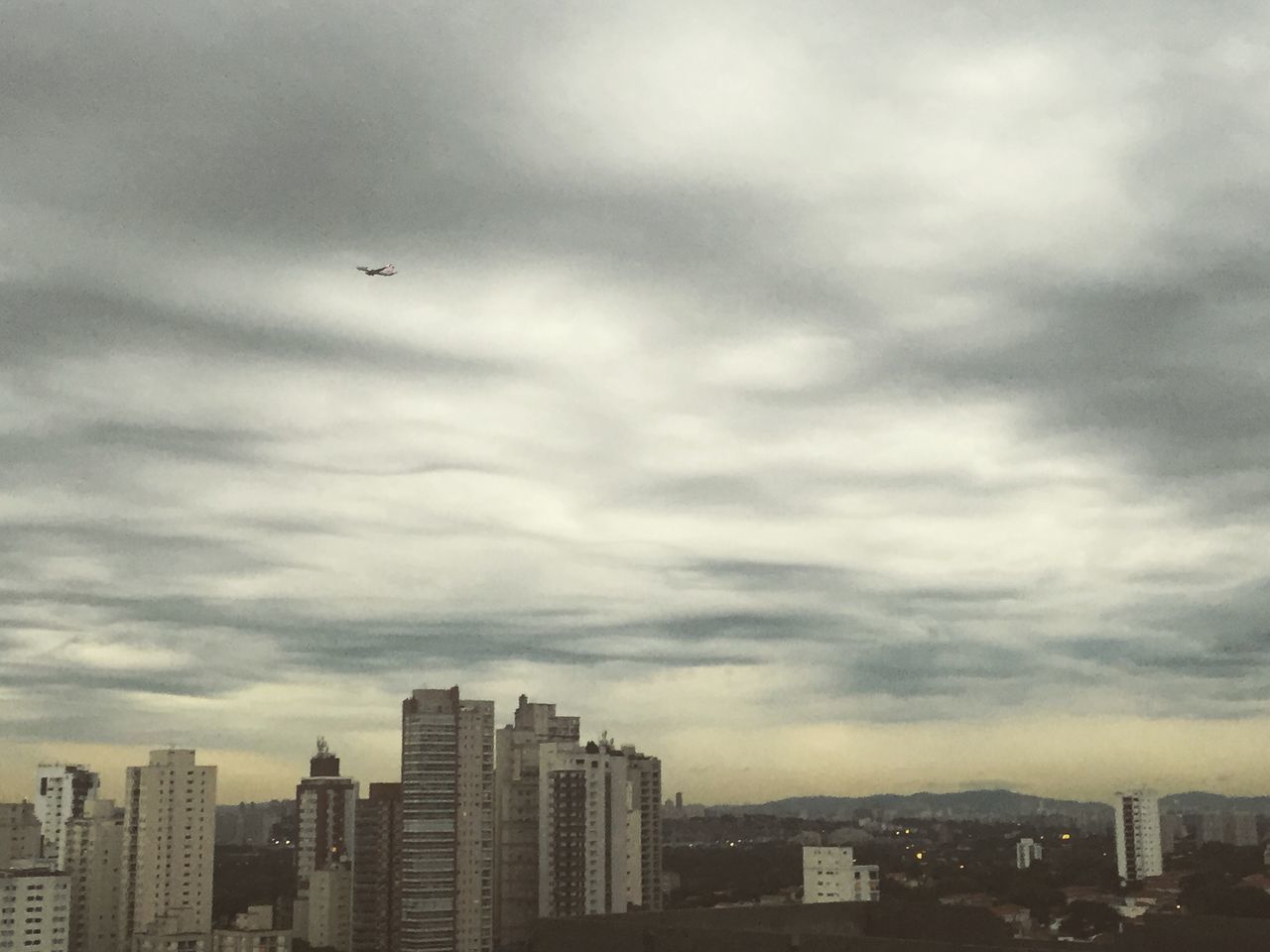 building exterior, architecture, city, built structure, sky, flying, cityscape, cloud - sky, skyscraper, cloudy, bird, modern, overcast, weather, cloud, city life, residential building, office building, urban skyline, building