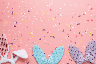 Directly above shot of bunny headband with confetti over colored background