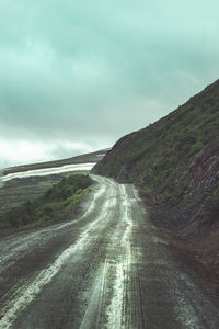 Road leading towards mountain against sky