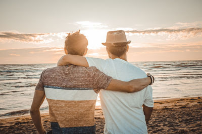 Rear view of couple at beach against sky