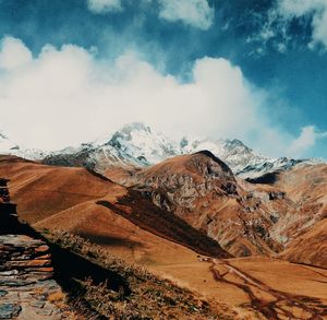 Scenic view of snowcapped mountains against cloudy sky