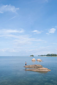 Person standing on rock in sea