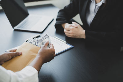 Close-up of client bribing lawyer at desk in office