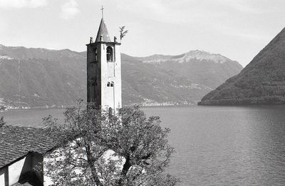 Lighthouse amidst trees and buildings against sky
