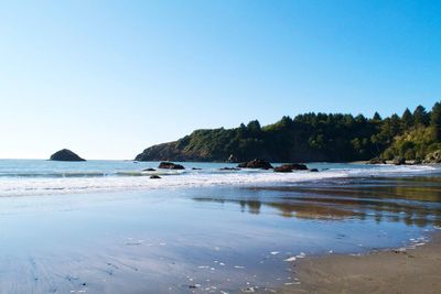 Scenic view of beach against clear blue sky