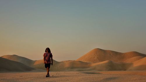 Full length of woman standing on desert against sky