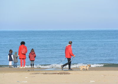 People walking on beach by sea against sky