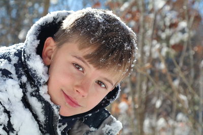 Close-up portrait of smiling boy in snow