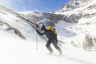 Hiker battles wind above black lake, rocky mountain national park