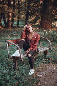 Portrait of young woman sitting on bench in park