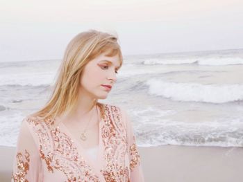 Young woman looking away while standing at beach