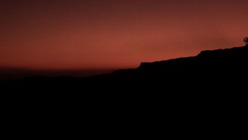 Scenic view of silhouette mountain against orange sky