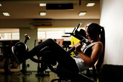 Side view of young woman exercising at gym