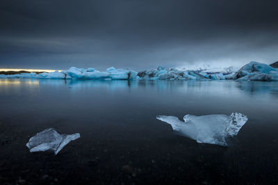 Scenic view of ice floating on lake against sky