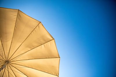 Low angle view of umbrella against clear blue sky