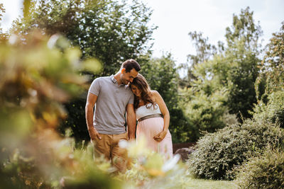 Husband with pregnant wife holding hands in forest