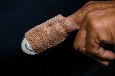 Close-up of man holding cigarette against black background