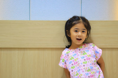 Portrait of girl standing against wall