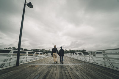 Men on bridge against sky