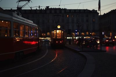 Illuminated railroad tracks in city at dusk