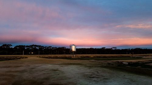 Built structure on field against sky at sunset