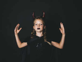 Portrait of girl wearing devil costume against black background