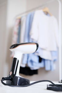 Hand steamer on the background of a rack with clothes in the room