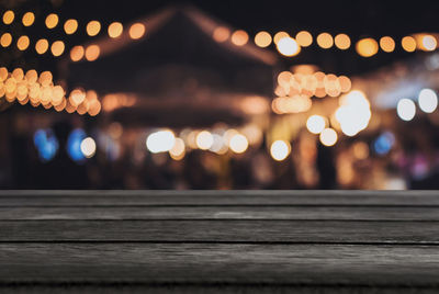 Close-up of table against defocused image of illuminated lights at night