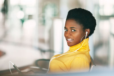 Portrait of an african girl who listens to music with headphones while waiting for public transport.