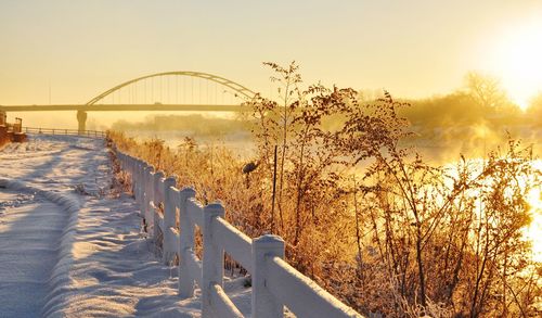 Snow covered path with bridge in background