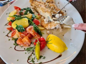 Close-up of hand holding salad served in plate
