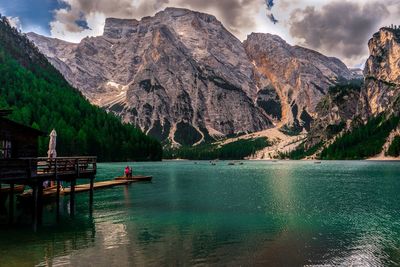 Scenic view of lake and mountains. people walking on water, watching boats float.