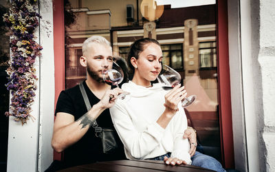 Young man and woman holding camera while sitting at home