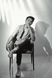 Portrait of young man sitting on chair at home