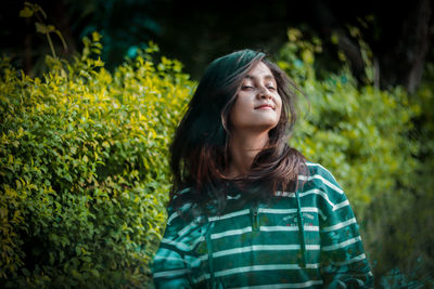 Beautiful woman standing against plants outdoors