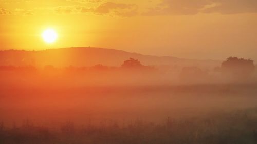 Scenic view of landscape against orange sky