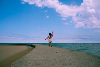Woman walking on beach by sea against sky