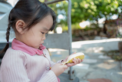 Girl eating fruit while standing outdoors